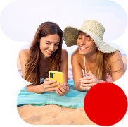 Dos jóvenes en la playa, utilizando el teléfono gracias a su tarifa móvil  