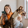 Una joven junto a su perro consultando su móvil  