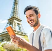 Un joven en París con la Torre Eiffel al fondo consultando su teléfono gracias a las tarifas con Roaming de Lowi 