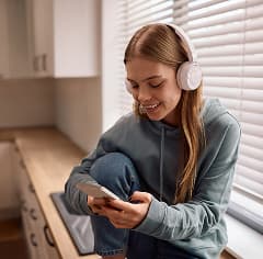 Mujer sonriendo y disfrutando de contenido en su teléfono móvil